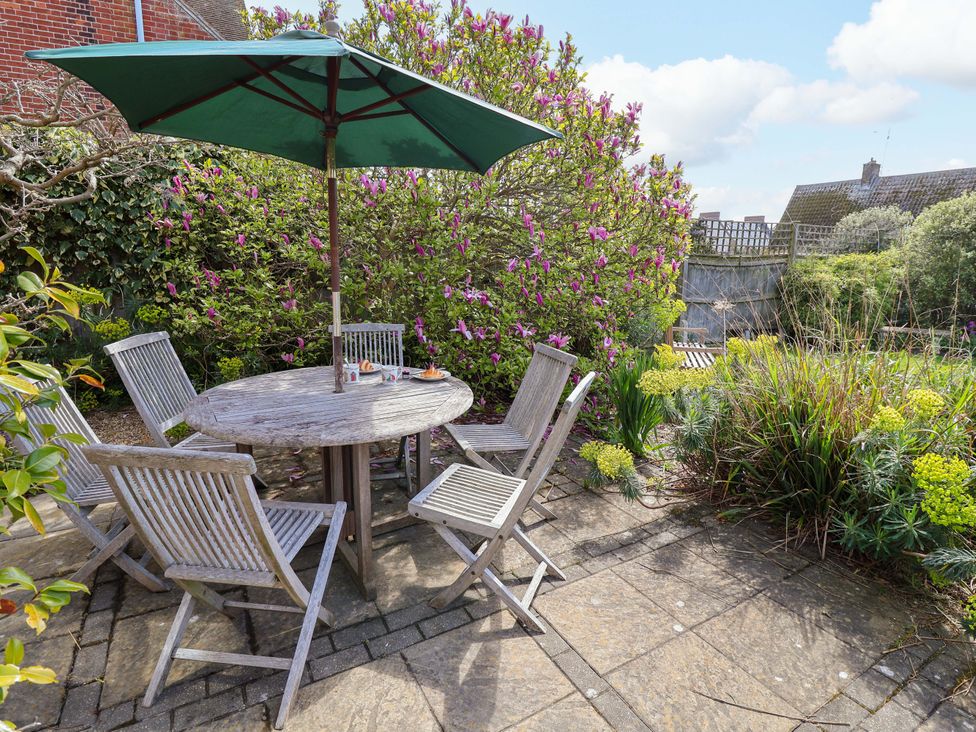 A garden with a table and chairs under an umbrella at Robert Sadler's Studio Aldeburgh