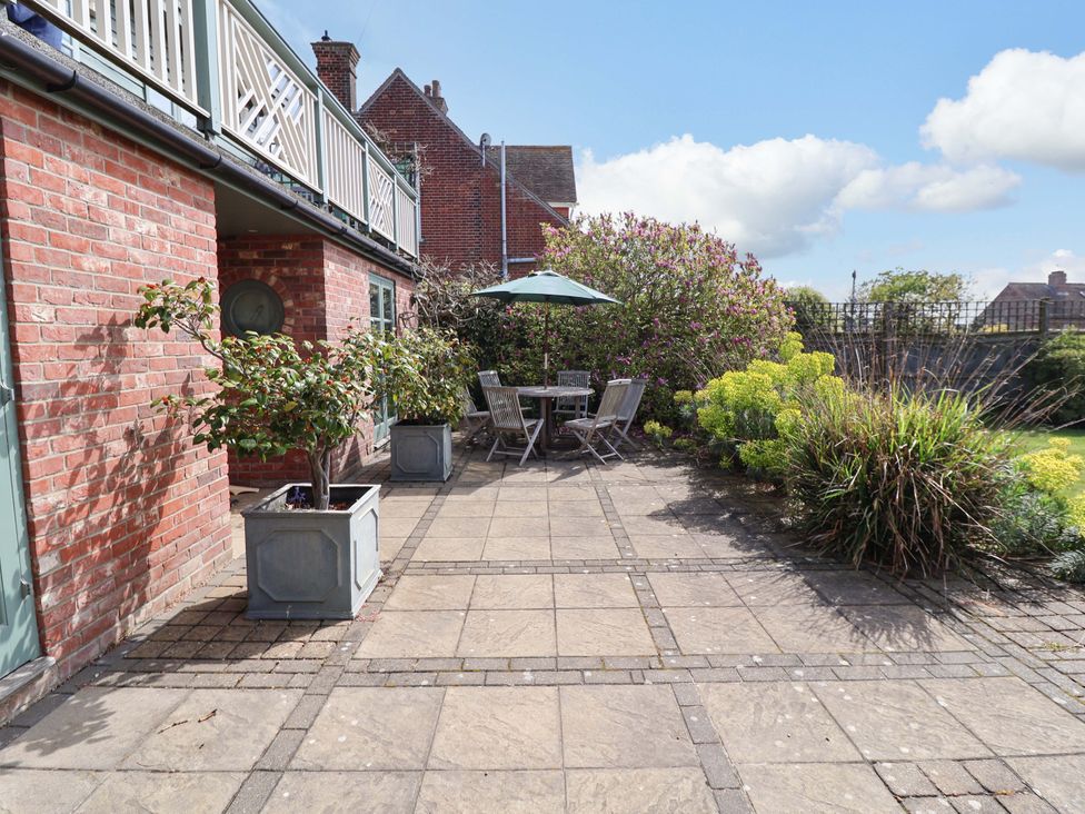 A garden with a patio, table, chairs, and plants at Robert Sadler's Studio in Aldeburgh