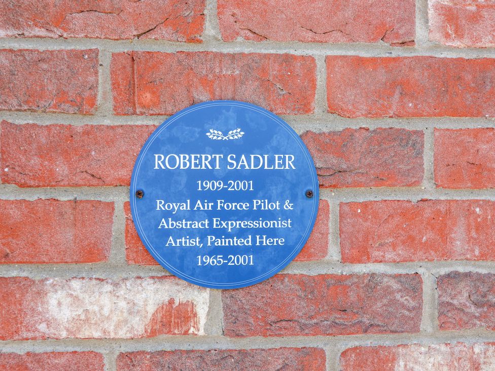 A plaque on a brick wall honoring Robert Sadler in Aldeburgh