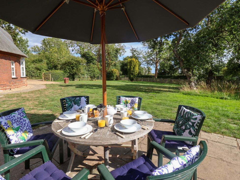 A dining table set with plates and drinks in the garden at The Round House in Easton near Framlingham
