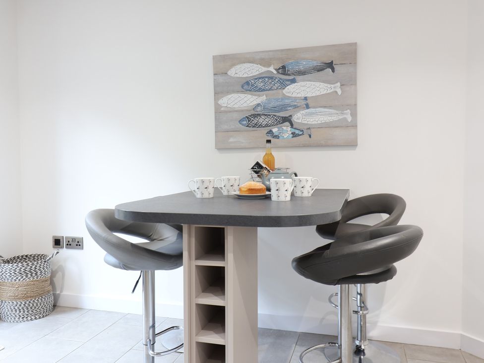 A kitchen with a bar table and stools at Corner Cottage, Thorpeness