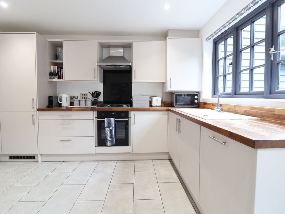 A kitchen with cabinets, oven, sink, and countertop at Corner Cottage, Thorpeness