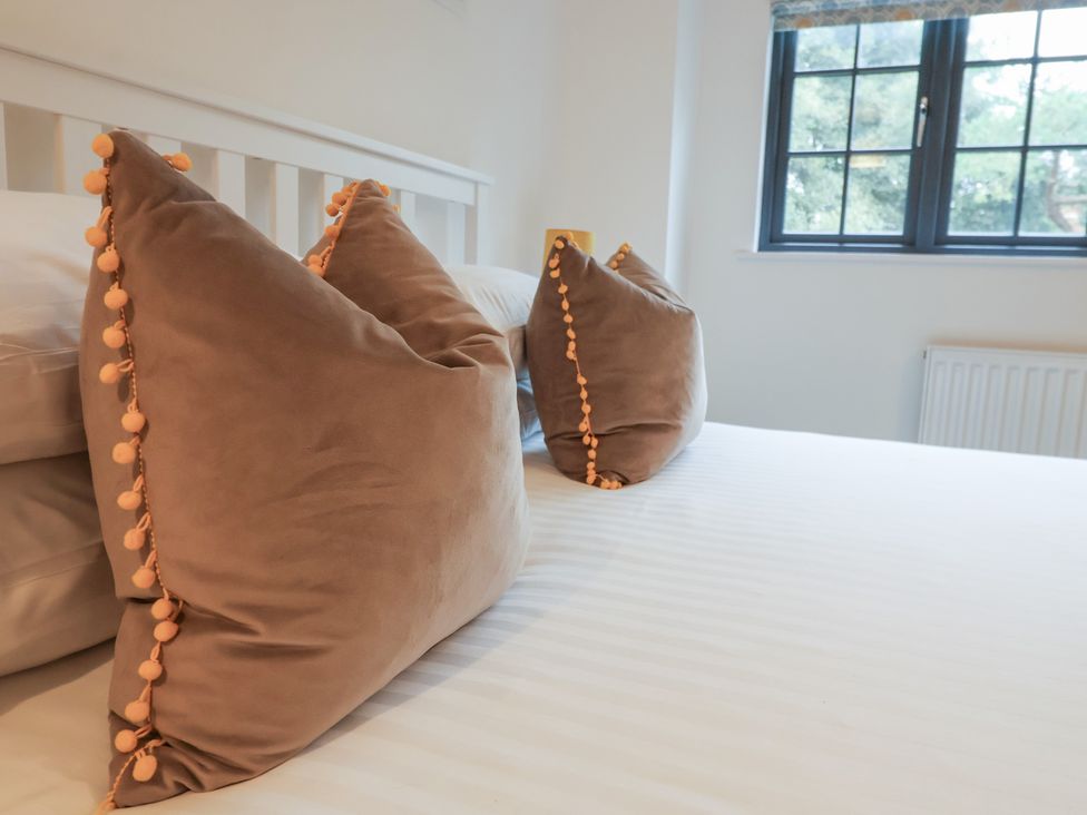 A bedroom with pillows on a bed at Corner Cottage, Thorpeness