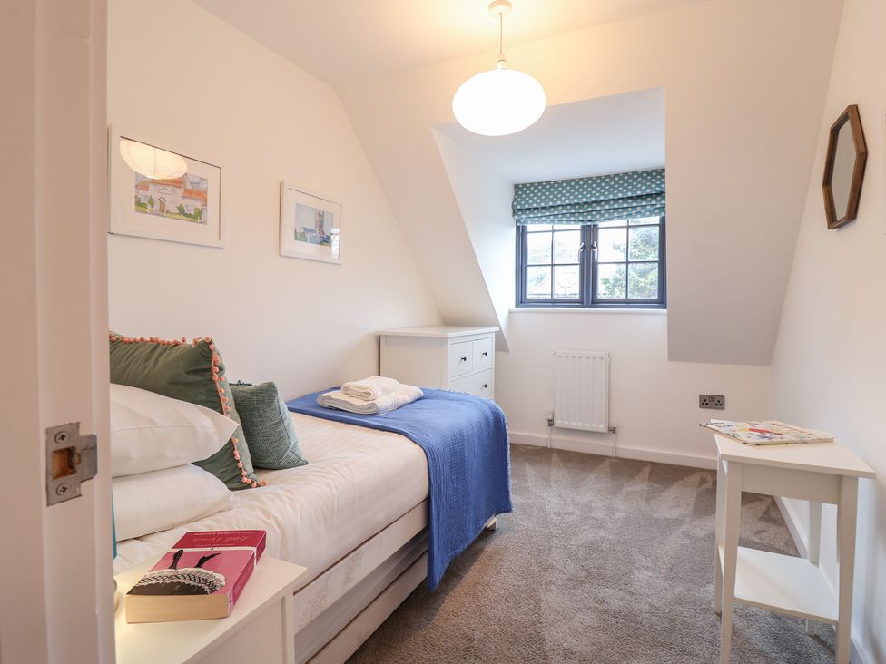 A bedroom with a bed, drawer unit and window at Corner Cottage, Thorpeness