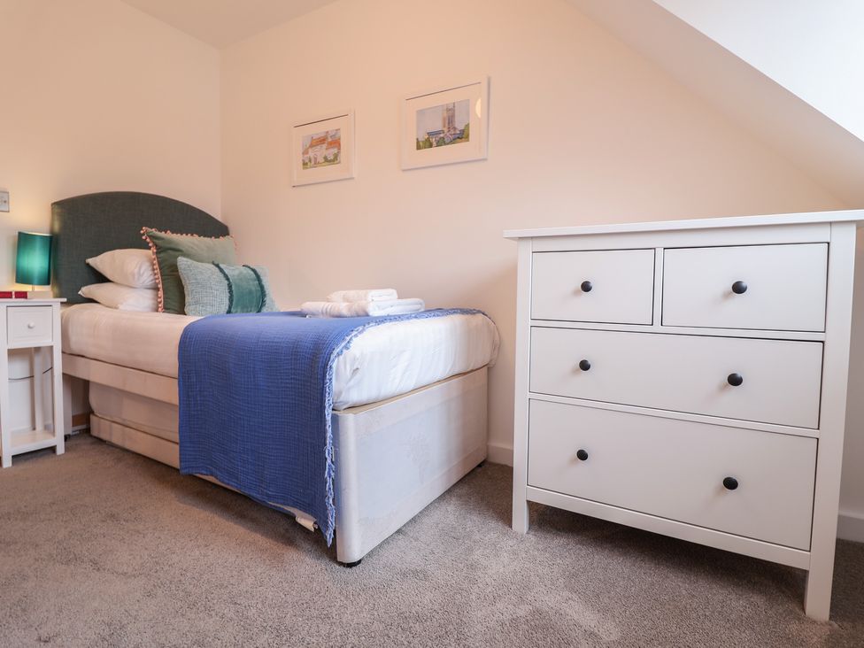 A bedroom with a bed and a dresser at Corner Cottage, Thorpeness