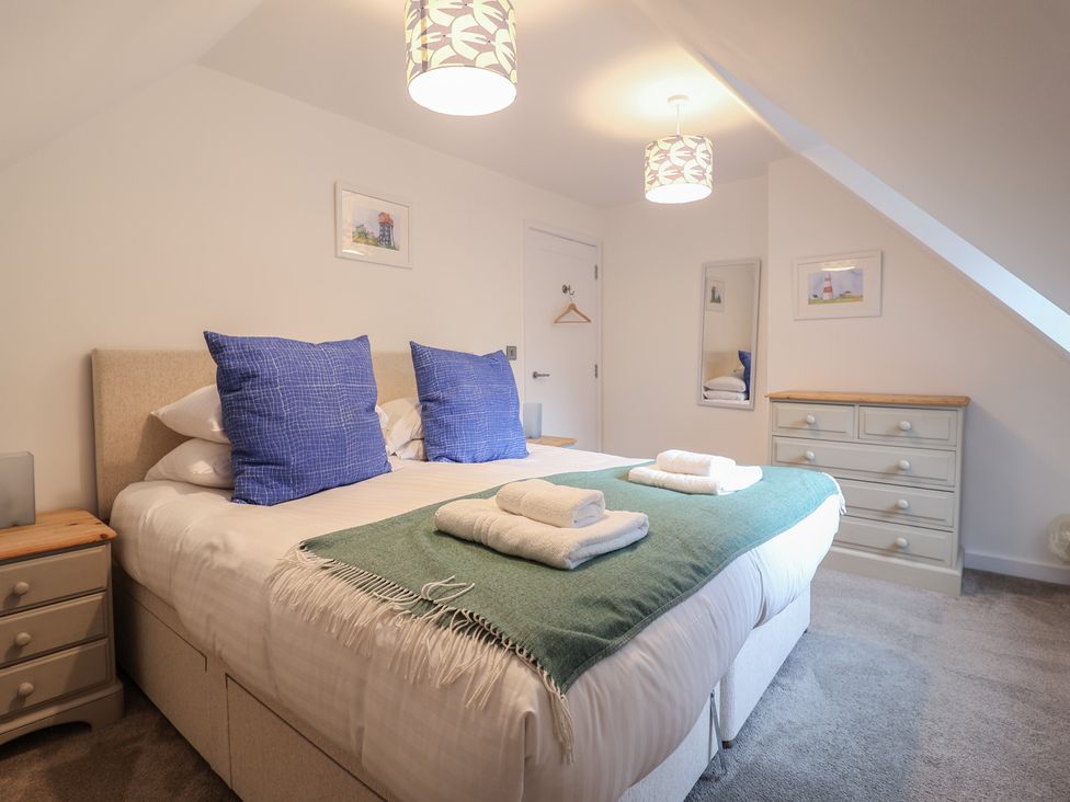 A bedroom with a bed and dresser at Corner Cottage, Thorpeness