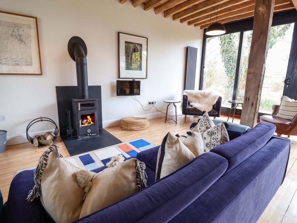 A living room with a wood stove and television at Fishpond House, Sotherton Halesworth
