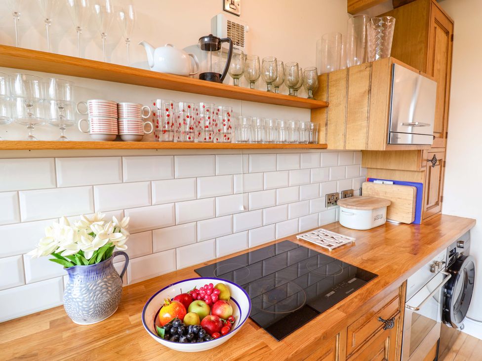 A kitchen with shelves holding glasses and mugs at Fishpond House, Sotherton in Halesworth