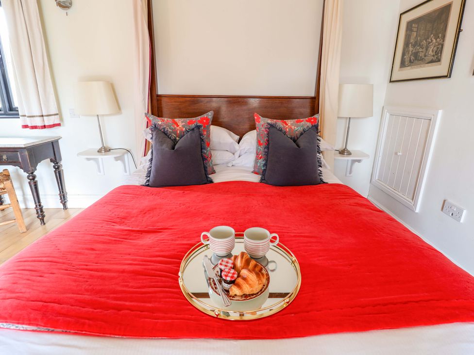 A bedroom with a red blanket and breakfast items at Fishpond House, Sotherton