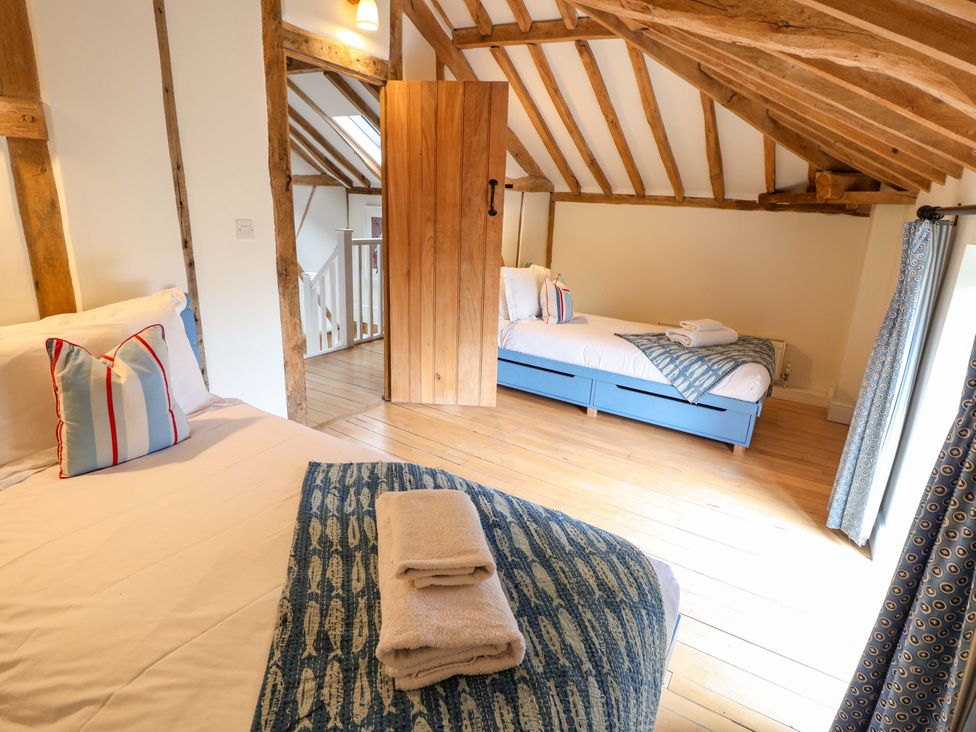 A bedroom with two beds and a door at Fishpond House, Sotherton Halesworth