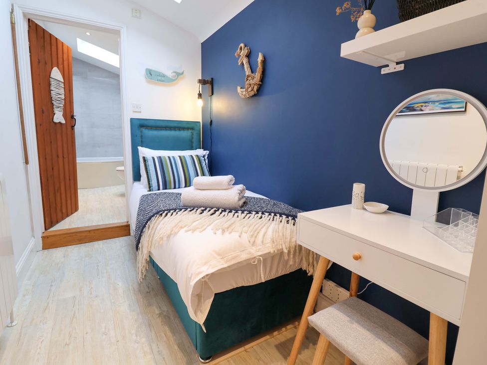 A bedroom with a bed and a desk at The Smokehouse Cottage in Southwold