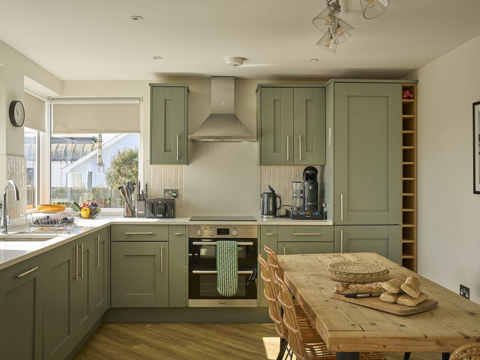 A kitchen with cabinets, oven, sink and dining table at Harbour Lights in Southwold