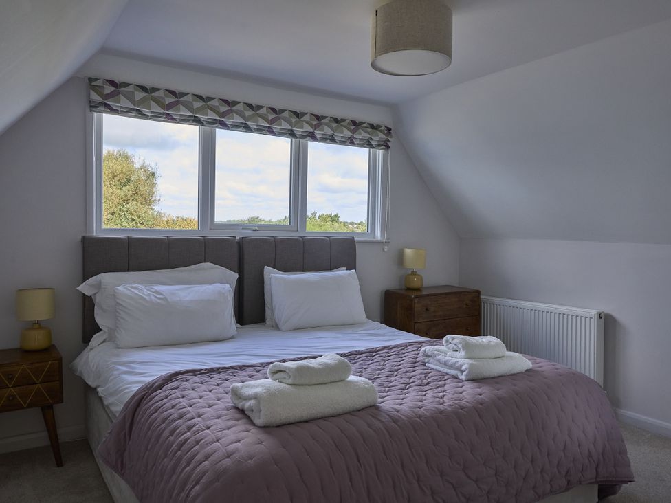 A bedroom with a bed and windows at Harbour Lights in Southwold