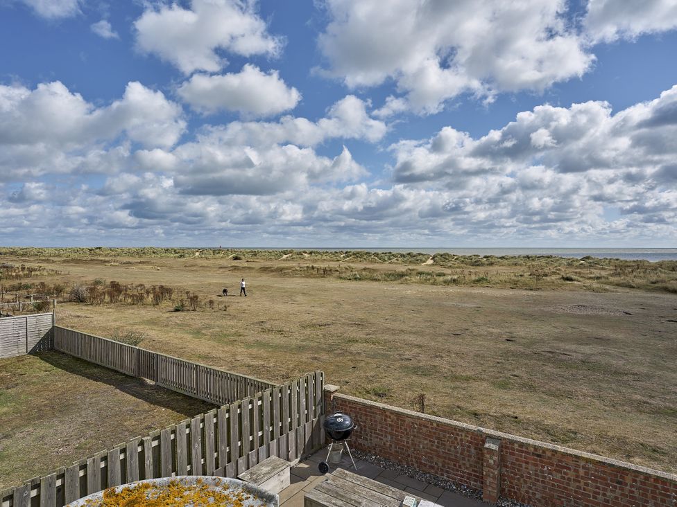 An outdoor area with a grill and a view of grass and sand dunes at Harbour Lights in Southwold