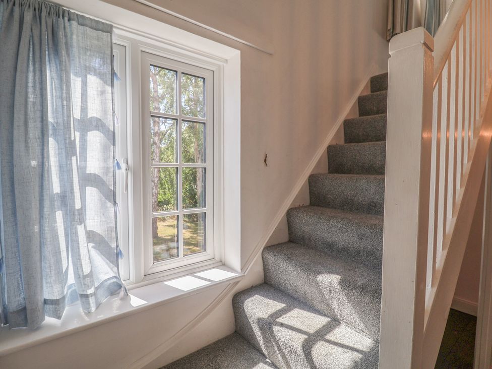 A staircase with a window and curtain at High Ground, Reydon