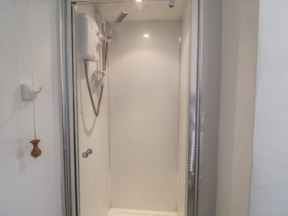 A shower with a glass door and water heater at High Ground, Reydon