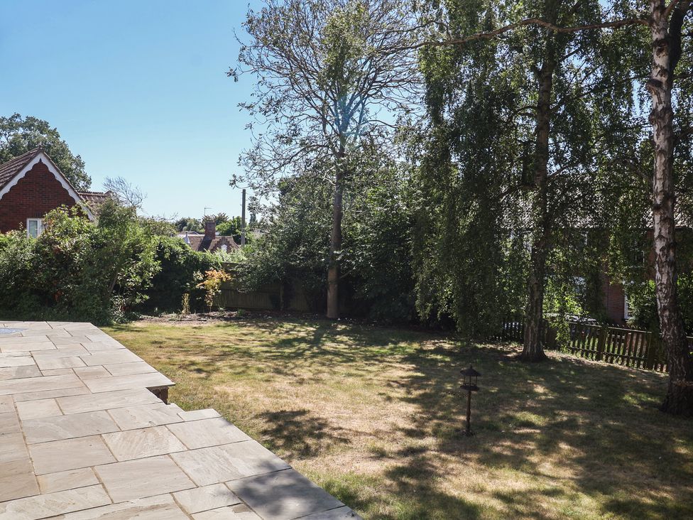 A garden with trees and a stone patio at High Ground, Reydon