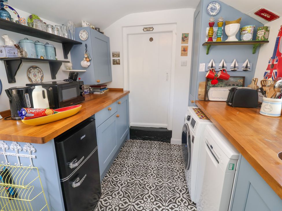 A kitchen with appliances and shelves at Cherry Tree Cottage, Woodbridge
