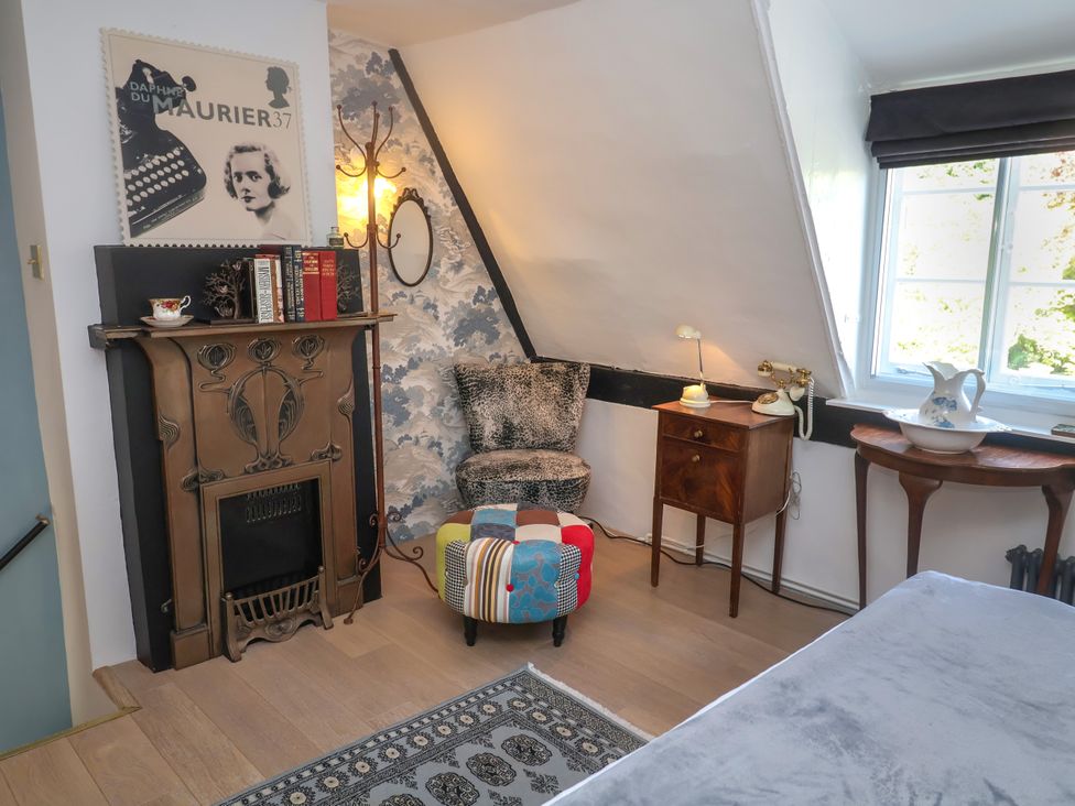 A bedroom with a fireplace and chair at Cherry Tree Cottage, Woodbridge