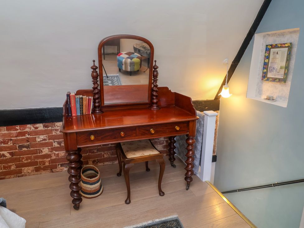 A vanity table with a mirror and books at Cherry Tree Cottage, Woodbridge