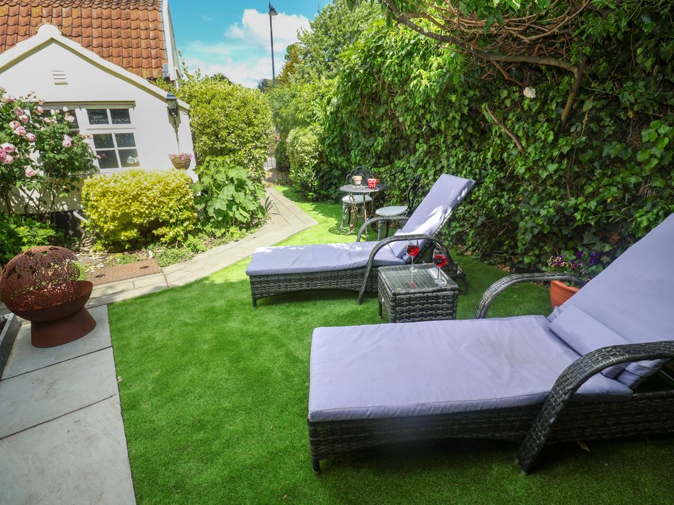 A garden with chaise lounges and a table at Cherry Tree Cottage, Woodbridge