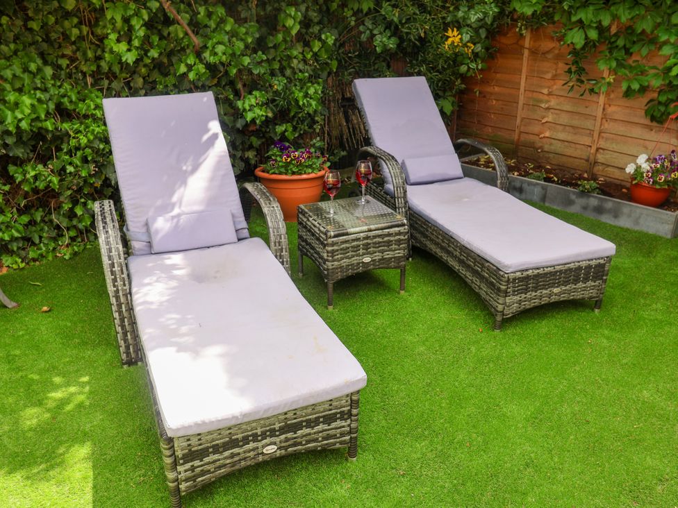 Two sun loungers and a glass table in a garden at Cherry Tree Cottage, Woodbridge