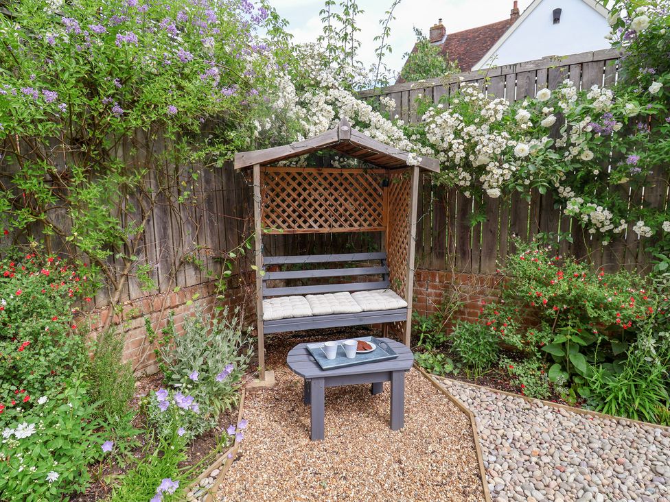 A bench with a table and cups in a garden at 1 Coconut Cottage, Long Melford