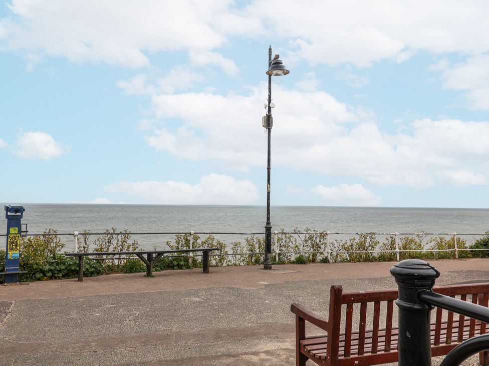 A coastal promenade with benches a lamppost a viewing telescope and a sea view at Dolphin Cottage Southwold