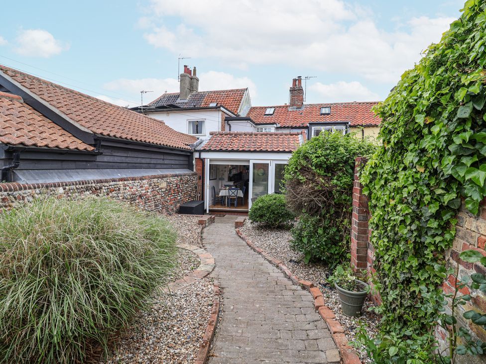 A garden pathway with bushes on either side leading to a house with tiled roofs at Dolphin Cottage Southwold