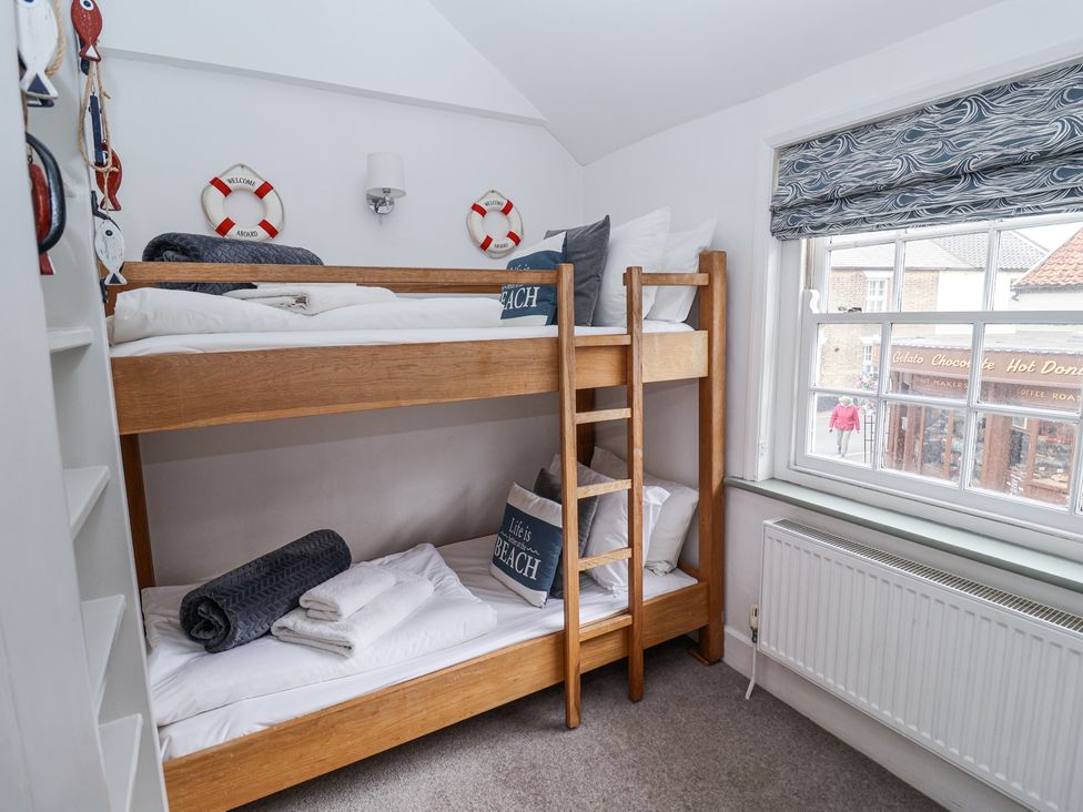 A bedroom with wooden bunk beds near a window and nautical decor at Dolphin Cottage Southwold