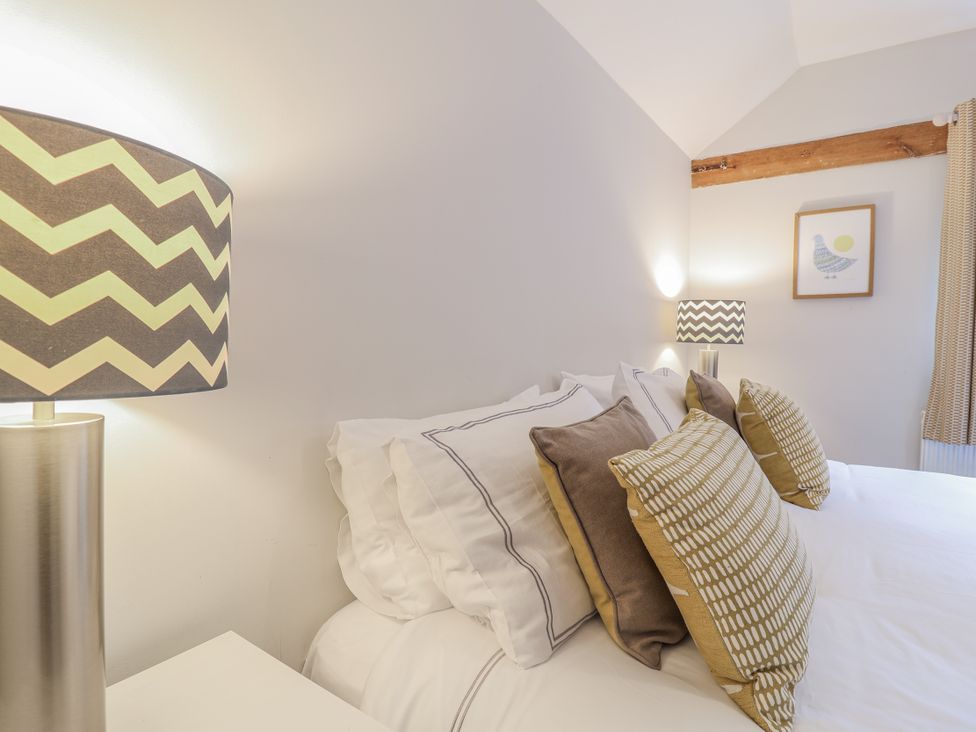 A bedroom with a bed and patterned pillows at Fig Cottage, Pettistree Near Woodbridge
