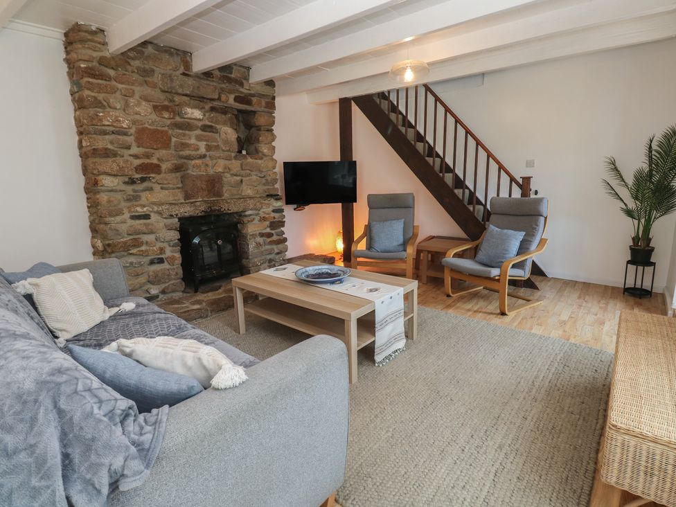 A living room with a fireplace and sofa at Candle Croft in Tolgus Mount near Redruth