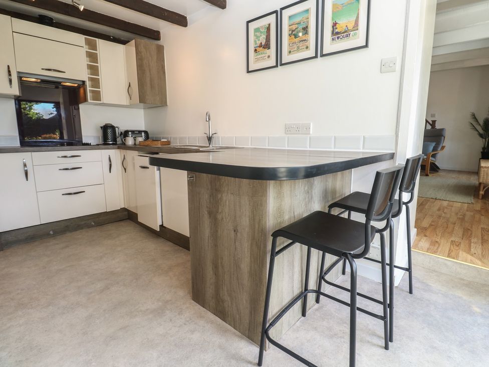 A kitchen with a bar counter and stools at Candle Croft in Tolgus Mount near Redruth