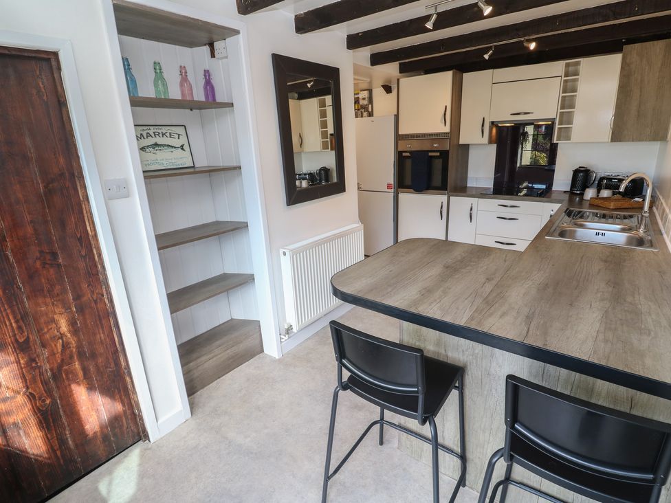 A kitchen with bar stools and open shelves at Candle Croft in Tolgus Mount near Redruth