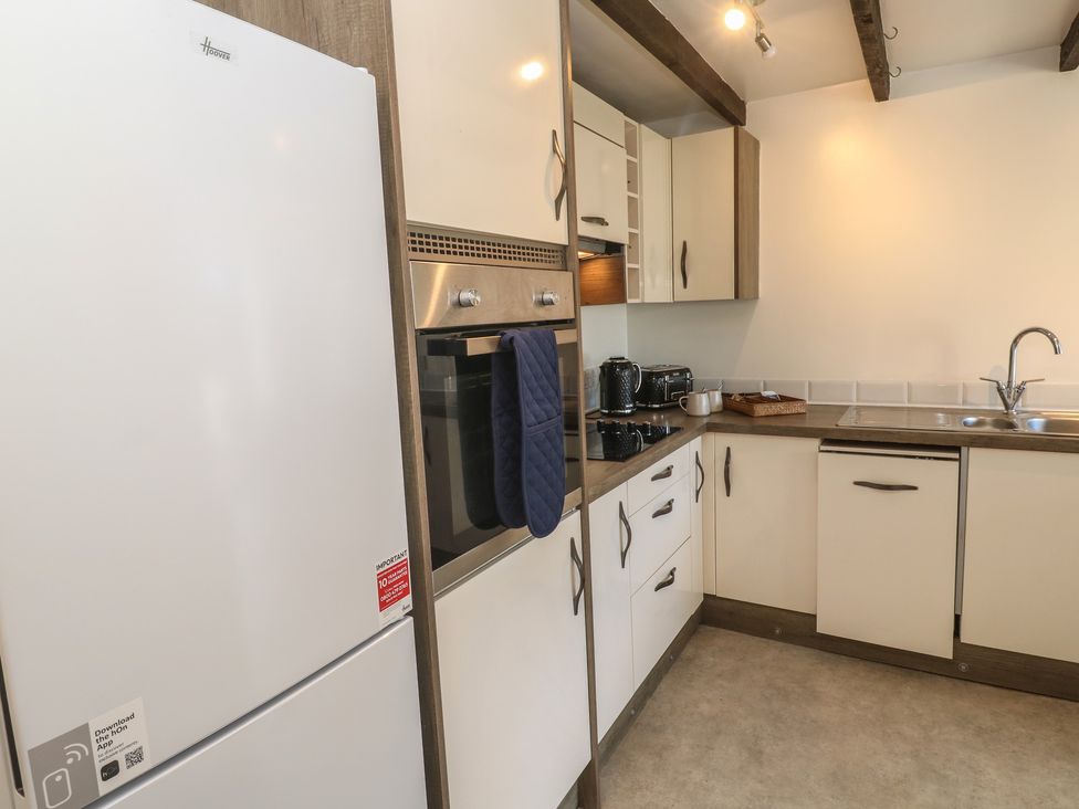 A kitchen with appliances including a refrigerator, oven, and sink at Candle Croft in Tolgus Mount near Redruth