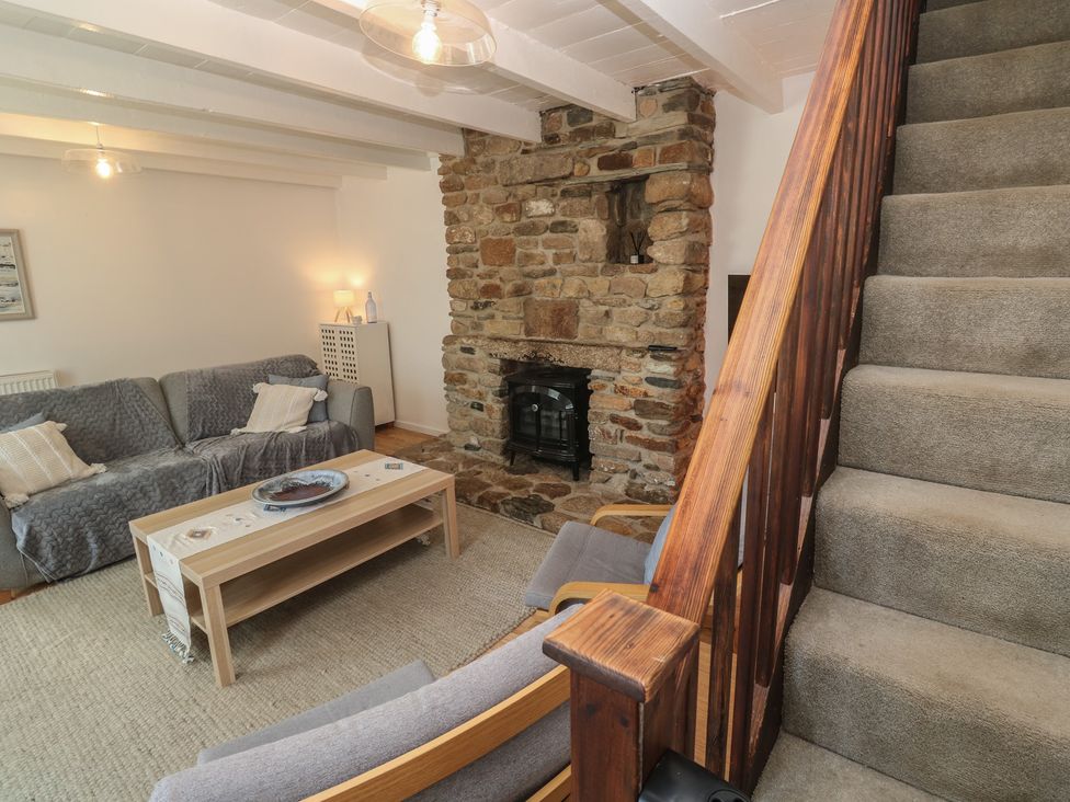 A living room with a sofa, coffee table, and fireplace at Candle Croft in Tolgus Mount near Redruth