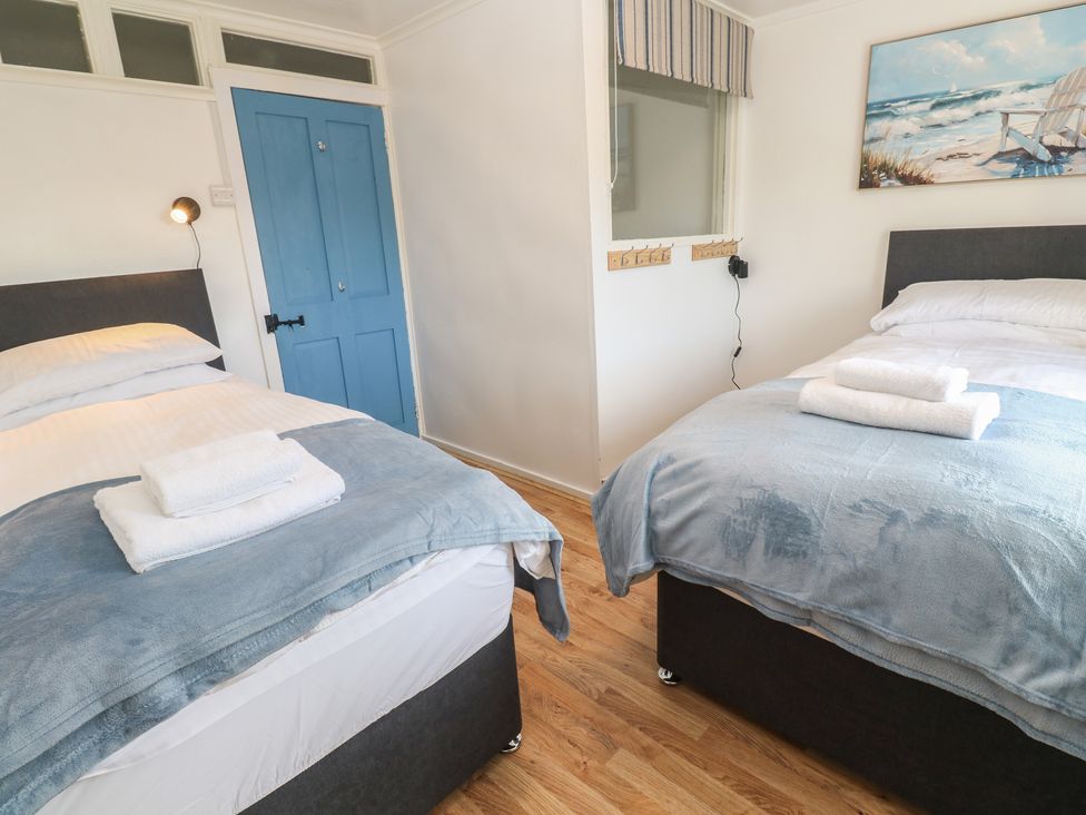 A bedroom with two beds and a blue door at Candle Croft in Tolgus Mount near Redruth