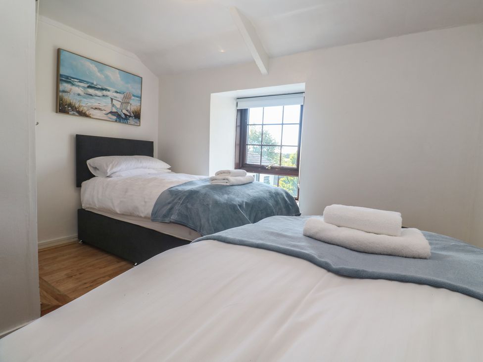 A bedroom with two single beds and a window at Candle Croft in Tolgus Mount near Redruth