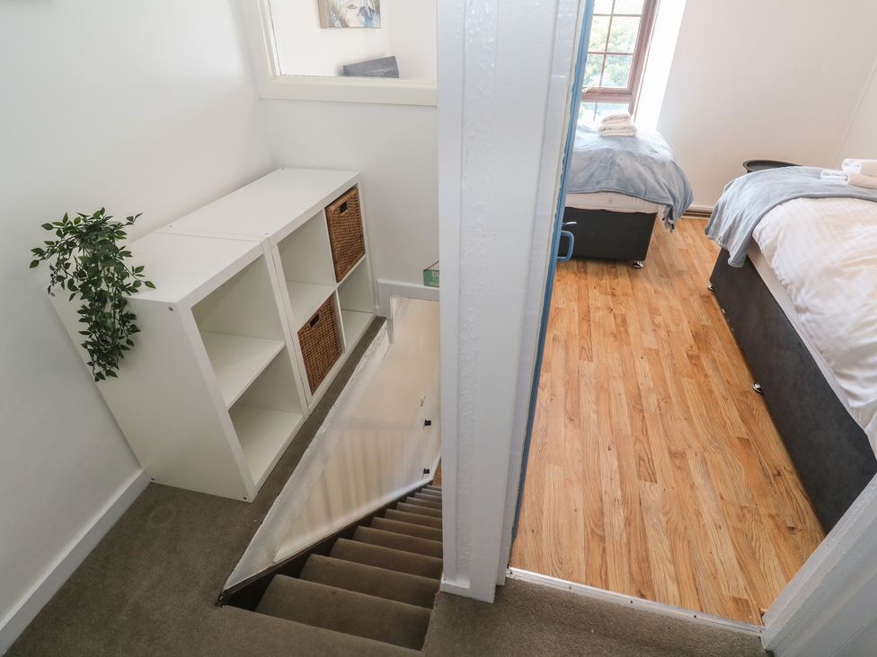 A bedroom with a staircase, shelf, and beds at Candle Croft in Tolgus Mount near Redruth