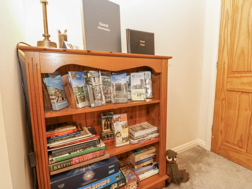 A bookshelf with guest information and books at Appletree Cottage in Richmond