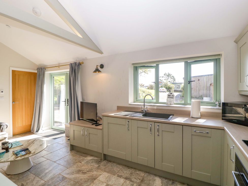 A kitchen with cabinets and a sink at Bottom Lodge in Penhow