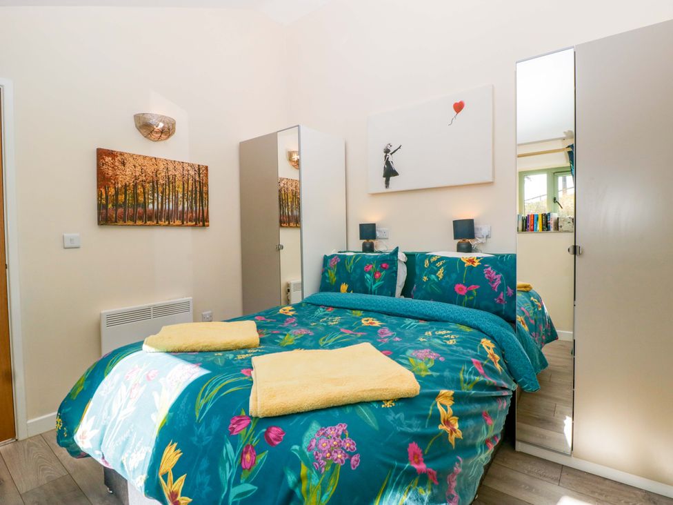 A bedroom with a bed and wall art at Bottom Lodge in Penhow