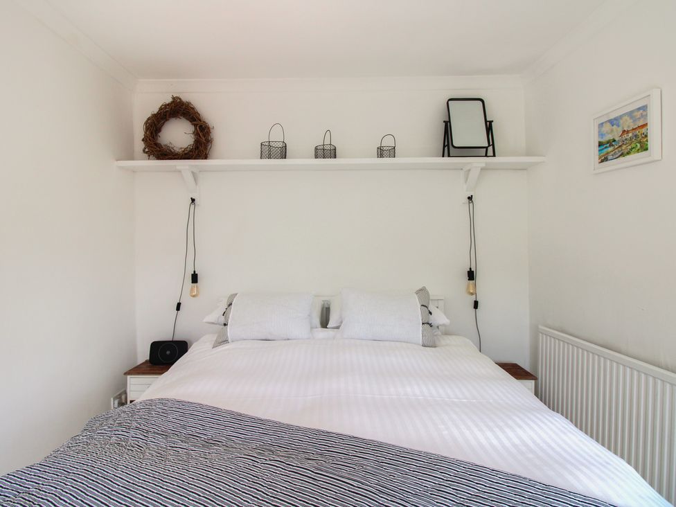 A bedroom with a bed and shelf at West Island in Kingsbridge