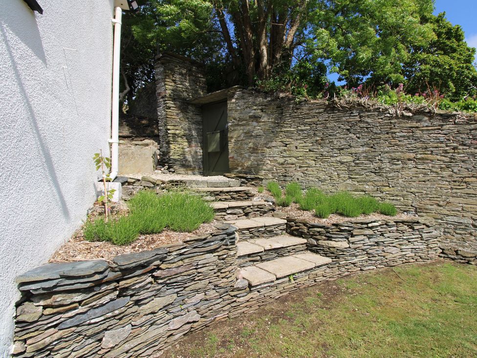 A garden with stone steps and a green door at West Island in Kingsbridge