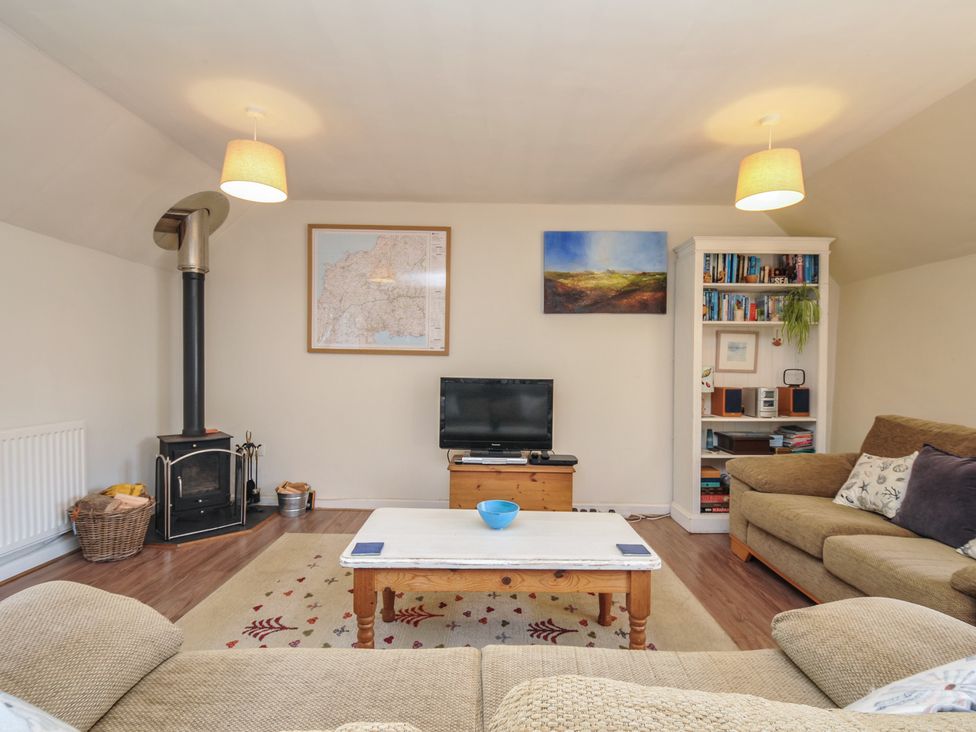 A living room with a sofa, television, and bookshelf at The Mews in Blisland