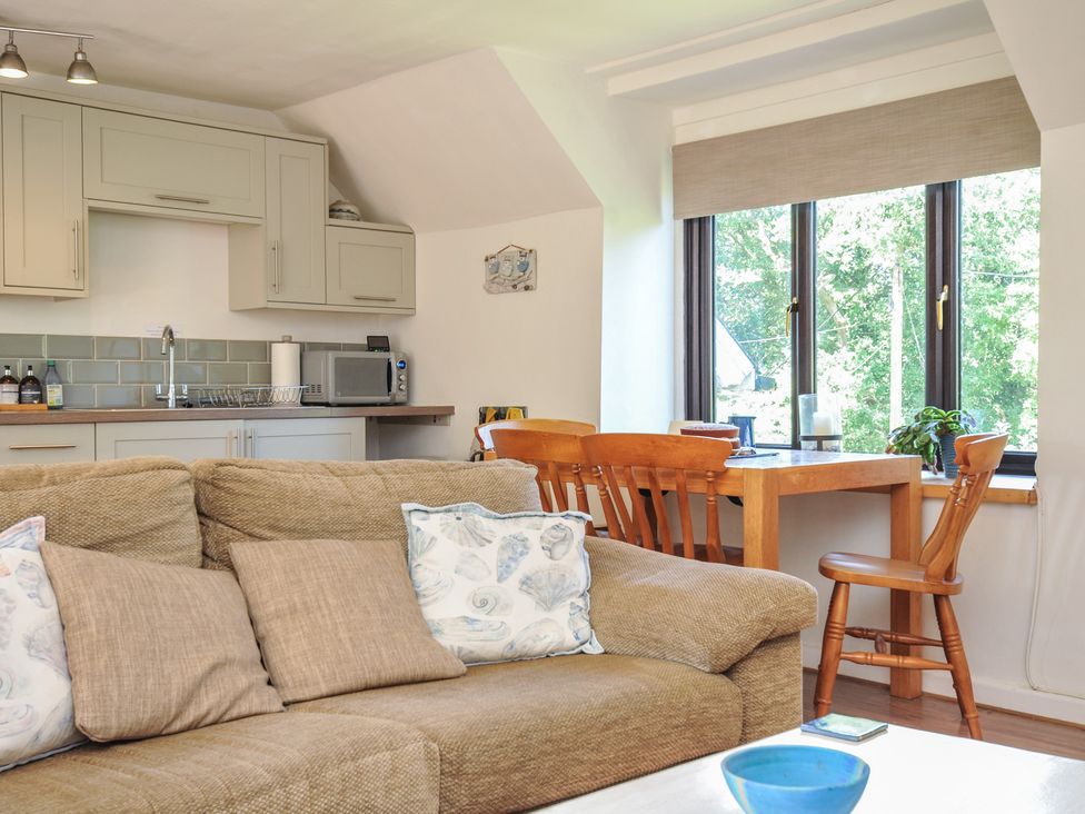 A living room with a sofa and dining area at The Mews in Blisland