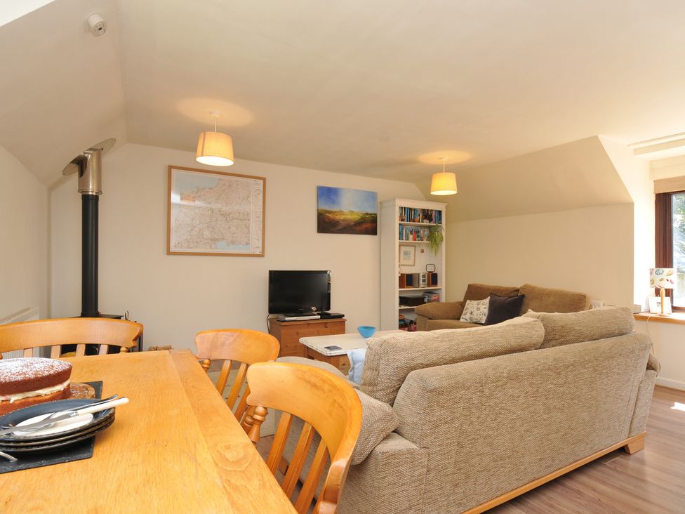 A living room with a dining table and television at The Mews in Blisland