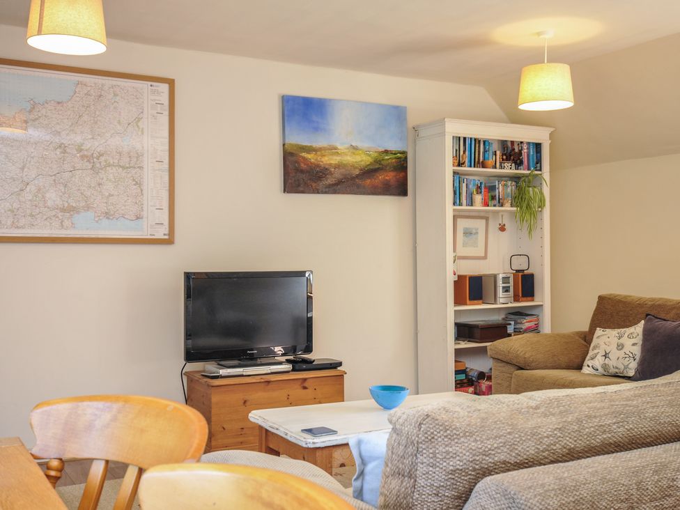 A living room with a television and books on a shelf at The Mews in Blisland