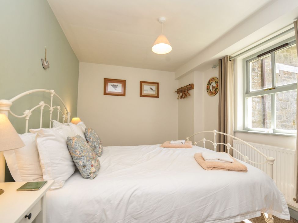 A bedroom with a bed and window at The Mews in Blisland