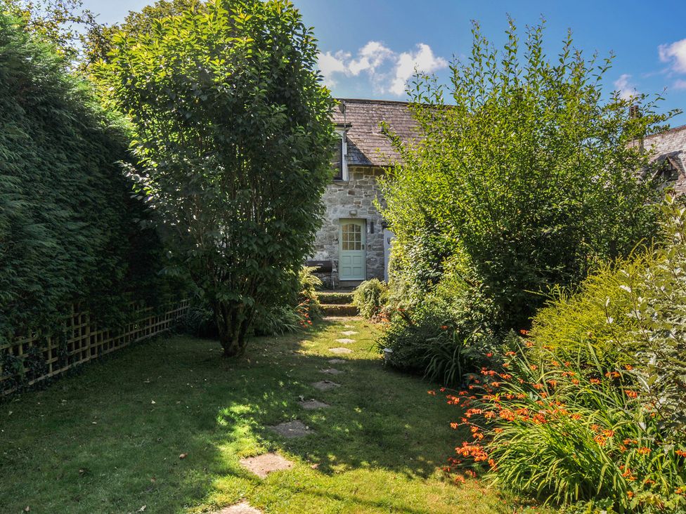 A garden with plants and a pathway leading to a door at The Mews in Blisland